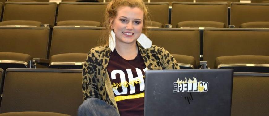 student in classroom with laptop